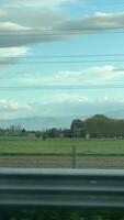 Enjoy a serene view of a green field, trees, mountains, and a fence beneath a clear sky video