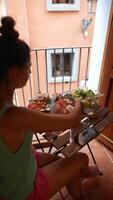 A woman is having brunch on a balcony with a city view, in a calm and comfortable setting video