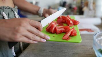 A chef chops fresh tomatoes on a cutting board, adding color to the kitchen workspace video