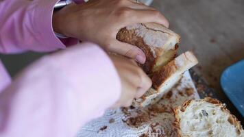 Hands slicing fresh bread on a wooden cutting board, creating an artisan culinary scene video
