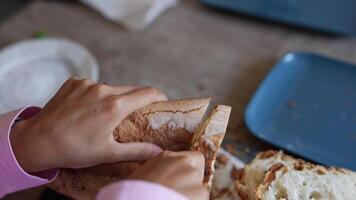 A person is enjoying the taste of a freshly baked loaf of bread on a blue plate at a table video
