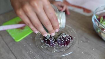 At a table, a person is garnishing a freshly prepared beetroot dish by sprinkling herbs video