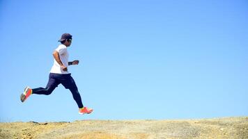 Man Running Outdoors on a Sunny Day with Clear Blue Sky in the Background photo