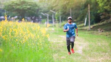 Man Jogging on a Scenic Nature Trail Surrounded by Greenery and Yellow Flowers on a Sunny Day photo