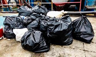 Piles of Black Garbage Bags on Concrete Ground in an Urban Setting photo