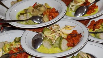 Lontong Sayur, served with chicken, balado potatoes, vegetables lodeh eggplant coconut milk and crackers photo