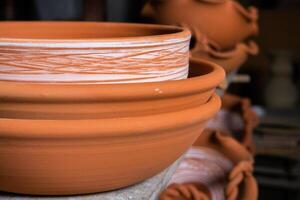 Freshly made clay mugs, pots and bowls drying up on wooden shelves in pottery workshop. Handmade ceramics manufacture. Different clay pots in workshop. photo