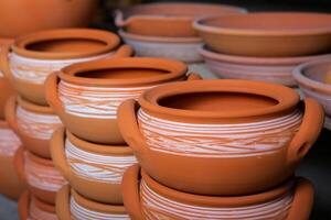 Freshly made clay mugs, pots and bowls drying up on wooden shelves in pottery workshop. Handmade ceramics manufacture. Different clay pots in workshop. photo