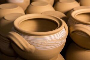 Freshly made clay mugs, pots and bowls drying up on wooden shelves in pottery workshop. Handmade ceramics manufacture. Different clay pots in workshop. photo