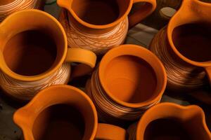 Freshly made clay mugs, pots and bowls drying up on wooden shelves in pottery workshop. Handmade ceramics manufacture. Different clay pots in workshop. photo