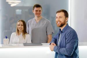 Grateful patient. Man standing at the reception of dental clinic and very pleased for the treatment. photo