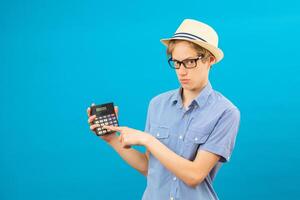 Surprised student holding calculator. Portrait of funny cute teen boy holding calculator in his hand. Shocked child with calculator looking at camera. photo