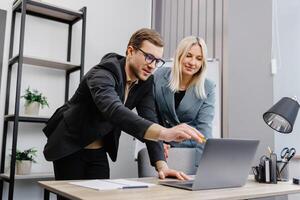 Concentrated male businessman looking at computer monitor, working with a young female worker on a project, people holding a meeting with a client or interviewing a job candidate. photo