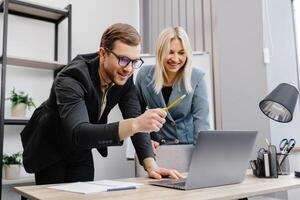 Concentrated male businessman looking at computer monitor, working with a young female worker on a project, people holding a meeting with a client or interviewing a job candidate. photo