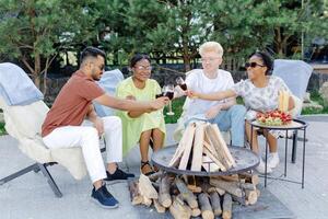 Friends rest together, drink wine, talk to each other on a picnic photo