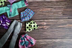 Groups of colorful small human doll fashion clothing object isolated on horizontal ratio empty copy spaced dark wooden surface table top background. photo