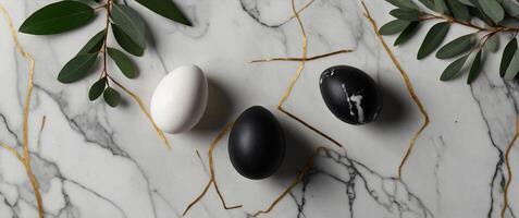 Frame of white and black Easter eggs decorated gold and eucalyptus leaves on marble table Flat lay, top view Happy Easter vertical banner design. photo