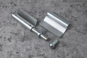 Photo from above of a fireproof iron hinge with a cement background