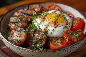 A bowl of black pudding, sliced and served with a poached egg and grilled tomatoes. photo
