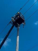 Electricians are climbing on electric poles to install and repair power lines with blue sky. Workers repairing power lines photo