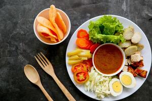 Gado-gado is a traditional Indonesian salad consisting of vegetables, potatoes, tempeh, tofu, carrots, tomatoes, lettuce, eggs and peanut sauce. Salad photo