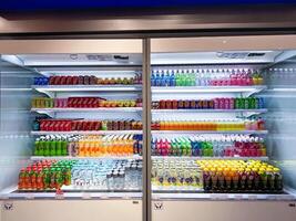 Yogyakarta, Indonesia - May 8, 2024. Various energy drinks, sodas, soft drinks, fruit juices, non-carbonated, milk in bottles and cans on the shelf of a grocery store supermarket, modern store. Drink photo