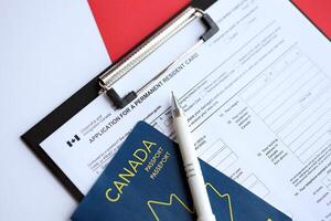 Application for permanent resident card on table with pen and canadian passport photo
