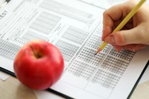 Female student hands testing in exercise and taking fill in exam paper sheet with pencil at school test photo
