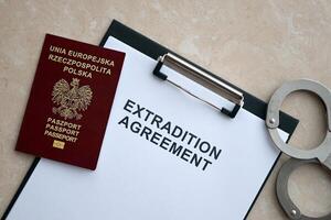 Passport of Poland and Extradition Agreement with handcuffs on table photo
