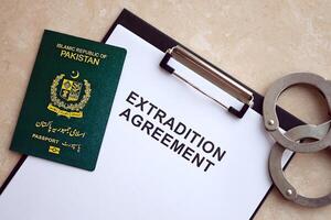 Passport of Pakistan and Extradition Agreement with handcuffs on table photo