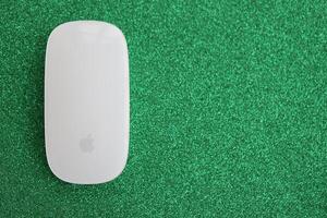 KYIV, UKRAINE - NOVEMBER 27, 2023 Apple Magic Mouse 3rd generation lies on sparkling glitter surface photo