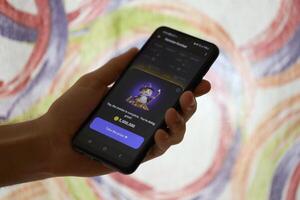 KYIV, UKRAINE - JUNE 26, 2024 Hamster Kombat telegram mini-game in tap 2 earn genre. Tap game on smartphone in hand photo