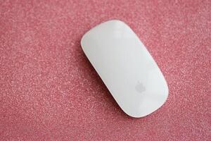KYIV, UKRAINE - NOVEMBER 27, 2023 Apple Magic Mouse 3rd generation lies on sparkling glitter surface photo
