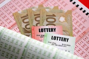 Lottery tickets lies with canadian dollars on gambling sheets with numbers for marking to play lottery photo
