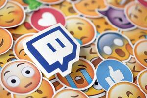 KYIV, UKRAINE - APRIL 20, 2024 Twitch logo and large set of stickers with Emoji yellow faces. Emoji is a pictogram or smiley embedded in text and used in electronic messages photo