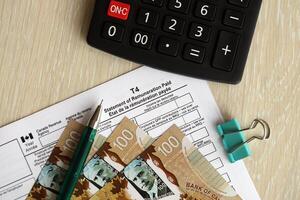Canadian T4 tax form Statement of remuneration paid lies on table with canadian money bills photo