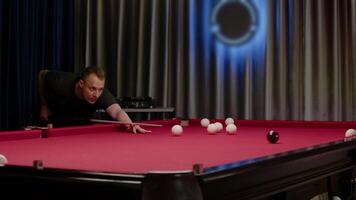 man är spelar slå samman på ett dyr biljard tabell, som är täckt i röd trasa. medium skott. långsam rörelse video