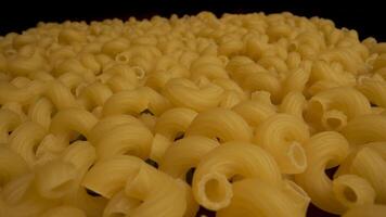 A close up shot of uncooked cavatappi pasta. The pasta is a pale yellow color and has a spiral shape. video