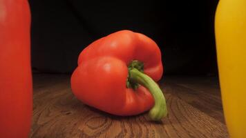 Red and yellow peppers on a wooden surface. The camera moves between the vegetables. Cooking concept. video
