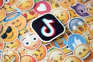 KYIV, UKRAINE - APRIL 20, 2024 TikTok logo and large set of stickers with Emoji yellow faces. Emoji is a pictogram or smiley embedded in text and used in electronic messages photo