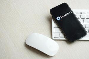 KYIV, UKRAINE - MARCH 17, 2024 DeepMind logo on iPhone display screen with apple keyboard and mouse on table photo