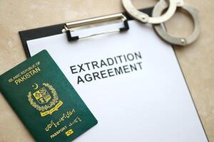 Passport of Pakistan and Extradition Agreement with handcuffs on table photo