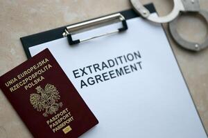 Passport of Poland and Extradition Agreement with handcuffs on table photo