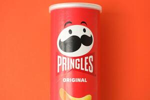 KYIV, UKRAINE - APRIL 20, 2024 Pringles original potato chips on red background. Pringles is a brand of potato snack chips photo