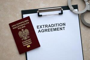 Passport of Poland and Extradition Agreement with handcuffs on table photo