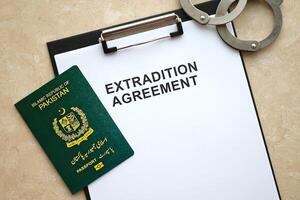 Passport of Pakistan and Extradition Agreement with handcuffs on table photo
