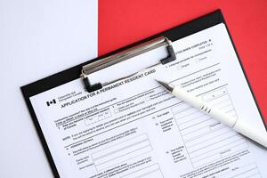 Application for permanent resident card on table with pen photo