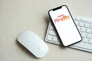 KYIV, UKRAINE - MARCH 17, 2024 Adobe Firefly logo on iPhone display screen with apple keyboard and mouse on table photo