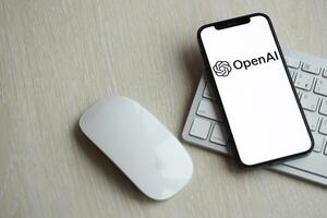 KYIV, UKRAINE - MARCH 17, 2024 OpenAI logo on iPhone display screen with apple keyboard and mouse on table photo