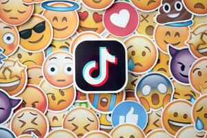 KYIV, UKRAINE - APRIL 20, 2024 TikTok logo and large set of stickers with Emoji yellow faces. Emoji is a pictogram or smiley embedded in text and used in electronic messages photo